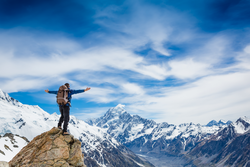 hiker at the top of a rock with his hands raised enjoy sunny day 